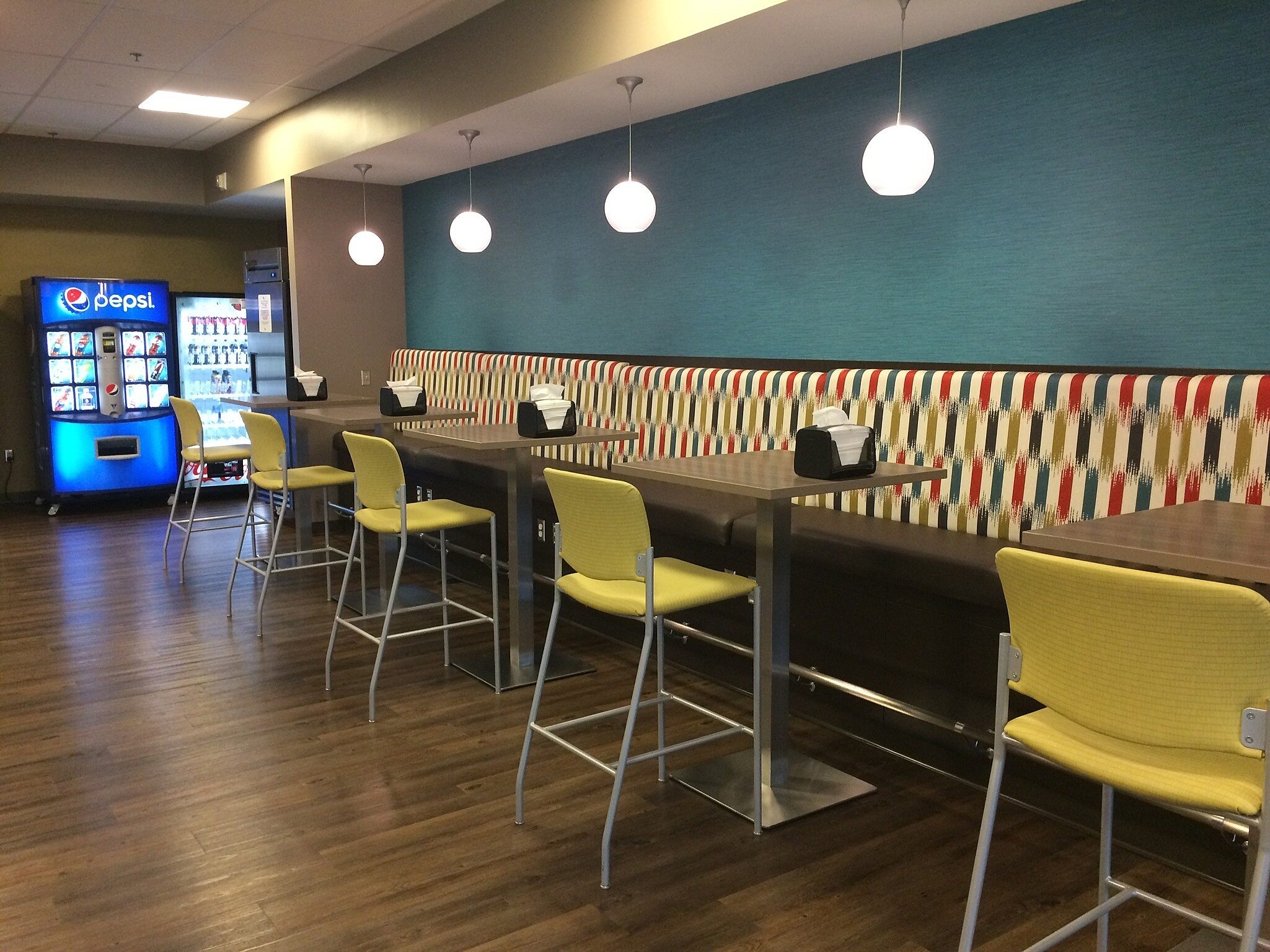 Bar height booth seating with yellow upholstery stools and pendant lighting.
