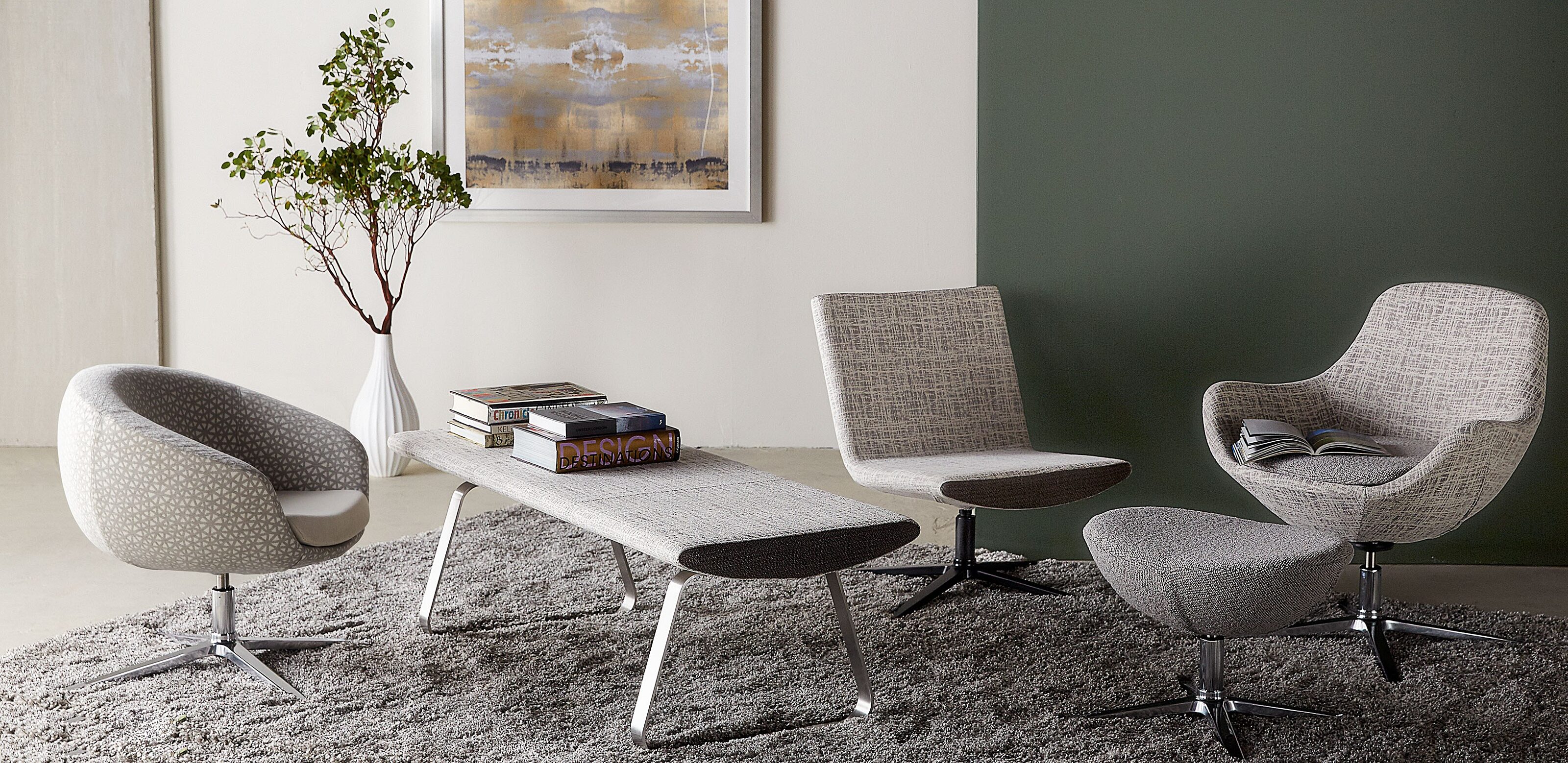collection of gray patterned lounge seating on plush gray rug in front of white and green walls