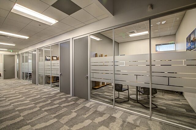 row of glass offices with opaque vinyl stripes on gray patterned carpet